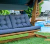 A wooden swing set with gray cushions is placed on a green lawn next to a swimming pool. Podgląd zdjęcia produktu