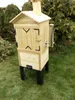 A wooden smoker is standing on a grassy lawn with trees in the background. Produktbild-Vorschau