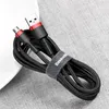 A black and red braided micro USB cable is coiled on a textured gray surface. Náhled obrázku produktu