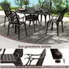 A set of garden chairs and a table on a patio with greenery in the background. Podgląd zdjęcia produktu