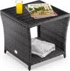 A polyrattan side table with a WPC tabletop, a glass of orange juice, and magazines on top. A folded towel is stored on the lower shelf. Anteprima dell’immagine prodotto
