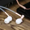 Close-up of in-ear headphones with white ear tips and rose gold accents, connected to a smartphone. Produktbild-Vorschau