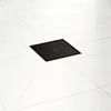 A black square drain is installed in a white tiled floor. Produktbild-Vorschau