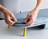 A person's hands are shown adjusting the cover of a small, foldable ironing board. Náhľad obrázku produktu