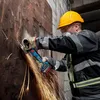 A person wearing safety gear is using a Bosch angle grinder to cut metal, creating sparks. Náhľad obrázku produktu