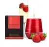 A red scented candle with a lit wick, a glass of champagne with strawberries, and a box of "Magnetifico" aphrodisiac sweet strawberry scented candles are arranged on a white background. Anteprima dell’immagine prodotto
