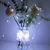 A string of white LED lights wrapped around a clear glass vase containing artificial flowers and greenery. Produktbild-Vorschau
