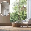 A modern living room with a large window overlooking trees, featuring a chair, coffee table, and a wall mirror. Anteprima dell’immagine prodotto