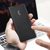 A person is holding a black phone case with a laptop in the background. Náhled obrázku produktu
