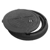 A black manhole cover and its frame are shown on a white background. The cover is slightly ajar, revealing two bolts and a small tool. Produktbild-Vorschau