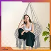 A woman sits in a hanging chair indoors, with a plant in the background. Voir les images du produit