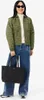 A woman is posing for a product shot, holding a black tote bag. Produktbild-Vorschau