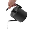 A hand holding a black kettle and pouring water. Podgląd zdjęcia produktu