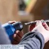 A close-up shot of a person's hands holding a blue power drill and a drill bit, demonstrating how to attach the bit to the drill. Produktbild-Vorschau
