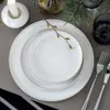 A table setting with plates, cutlery, a candle, and greenery. Náhled obrázku produktu
