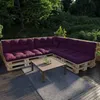 A sectional sofa made from wooden pallets with purple cushions, placed on a wooden deck with a coffee table and a rug. Voir les images du produit