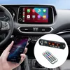 A person is holding a smartphone in a car, with the car's dashboard and infotainment screen visible. A small audio decoder board and remote control are shown in a circular inset. Produktbild-Vorschau