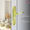 A close-up of a gold door handle on a door, with a blurred interior scene in the background. Produktbild-Vorschau