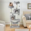 A multi-level cat tree with three cats is shown in a living room setting, next to a sofa and a chair. Produktbild-Vorschau