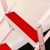 Close-up view of the red steps of a silver folding ladder. Produktbild-Vorschau