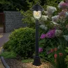 A black lamppost stands in a garden with hydrangeas and other plants. Produktbild-Vorschau