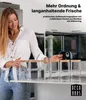 Frau in einer Küchenumgebung, die fünf klare Glasaufbewahrungsbehälter mit Bambusdeckeln anordnet Náhľad obrázku produktu