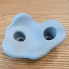 A light blue climbing hold with two circular indentations sits on a wooden surface. Voir les images du produit