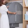 A woman is organizing clothes in a closet using garment bags. Produktbild-Vorschau