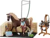 A toy horse, a girl, and stable accessories are arranged on a black surface against a white background. Produktbild-Vorschau