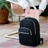 A person is placing a pink laptop sleeve into a black backpack. Produktbild-Vorschau