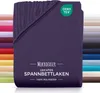 A folded purple fitted sheet is shown, with a stack of other colored sheets in the background. Produktbild-Vorschau