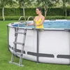 A woman in a yellow swimsuit stands in an above-ground swimming pool, holding onto the ladder. Produktbild-Vorschau