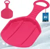 A pink plastic snow sled with a handle, shown on a snowy background. Voir les images du produit