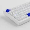 A close-up, angled view of a white mechanical keyboard with blue keycaps. Produktbild-Vorschau