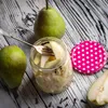 A close-up shot of pears and a jar of preserved pears on a wooden table. Voir les images du produit