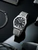 A close-up shot of a men's wristwatch with a black dial and silver metal band, placed on a reflective black surface. Anteprima dell’immagine prodotto