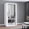 A white wardrobe with mirrored doors stands in a modern living room with gray walls and wooden flooring. A sofa and coffee tables are visible in the reflection. Produktbild-Vorschau