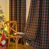 A Christmas-themed scene with a decorated Christmas tree, a wooden chair with a candle and some decorative items on it, and plaid curtains in the background. Produktbild-Vorschau