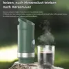 A portable coffee maker is shown on a rock, with steam rising from a cup of coffee next to it. The background is a blurred green outdoor scene. Produktbild-Vorschau