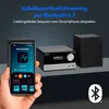 A hand holding a smartphone displaying a radio app, with a compact audio system and a speaker in the background. The scene suggests wireless music streaming via Bluetooth. Produktbild-Vorschau
