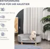 A small dog sits on a gray pet sofa in a room with sheer curtains and a plant. Produktbild-Vorschau