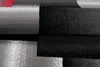 A close-up view of a textured fabric with a geometric pattern in black, gray, and red. Produktbild-Vorschau