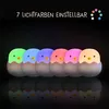 A row of seven glowing chick-shaped night lights in different colors, each emerging from an eggshell. Produktbild-Vorschau