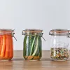 Three Kilner jars filled with preserved food items are arranged on a wooden surface against a white background. Produktbild-Vorschau