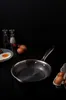 A frying pan with a honeycomb pattern is shown on a dark surface, with eggs and toast in the background. Náhľad obrázku produktu