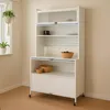 A white kitchen cabinet with glass doors and wooden bowls on shelves, placed in a room with light walls and wooden flooring. Anteprima dell’immagine prodotto