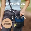 A person wearing a blue top and gray jeans is holding a blue treat pouch for dogs. Produktbild-Vorschau