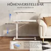 A white adjustable height side table is shown in a living room setting next to a sofa. Voir les images du produit