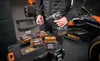 A person is holding a DeWalt drill with several DeWalt bit cases in front of a race car. Voir les images du produit