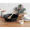 A cast iron pan with a wooden handle sits on a kitchen counter next to some decorative Christmas greenery. Produktbild-Vorschau